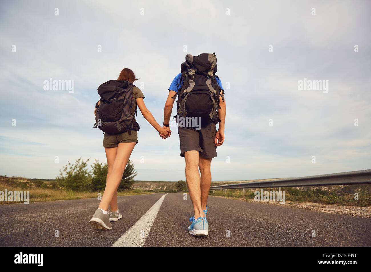 Reisende mit Rucksäcken weiter auf der Straße in der Natur Stockfoto