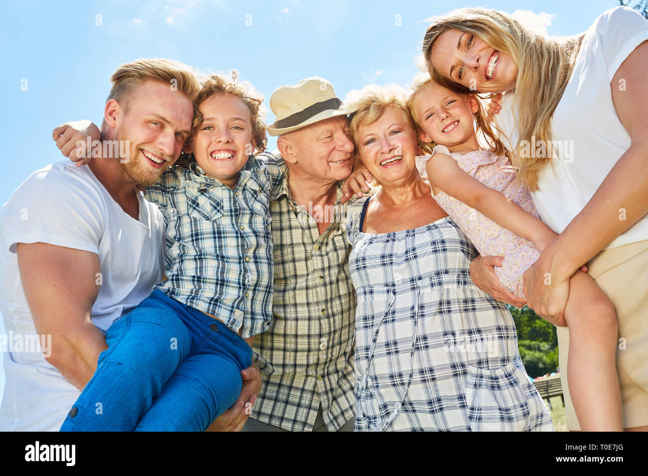 Erweiterte Familie mit Großeltern und Kindern lacht glücklich in die Kamera Stockfoto
