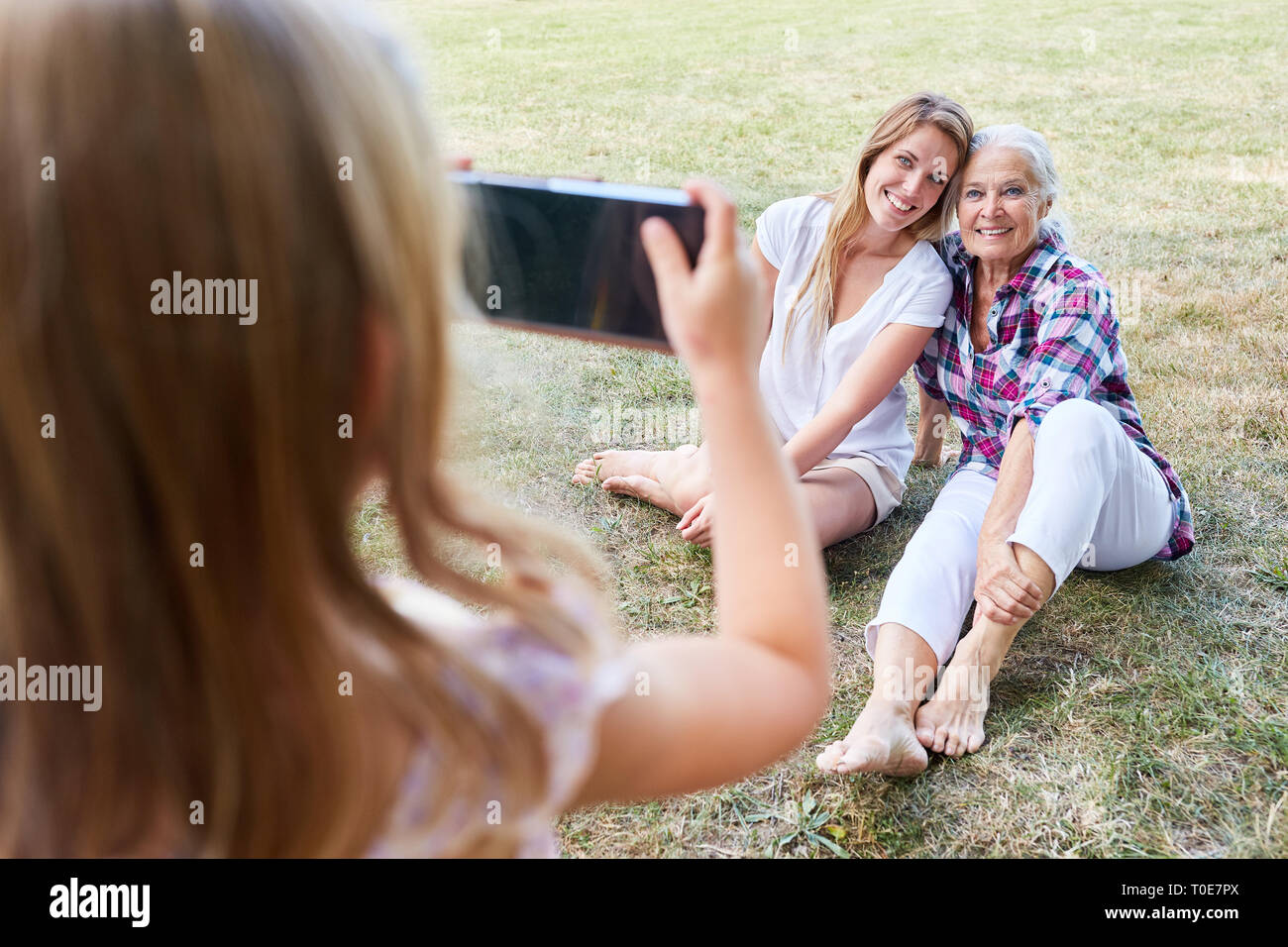 Kleines Mädchen Fotos Granny und ihre Mutter im Garten mit dem Smartphone Stockfoto
