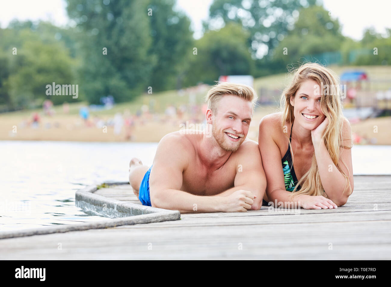 Junges Paar liegt entspannt auf einem Steg am Meer oder einem See auf Ferienhäuser Stockfoto