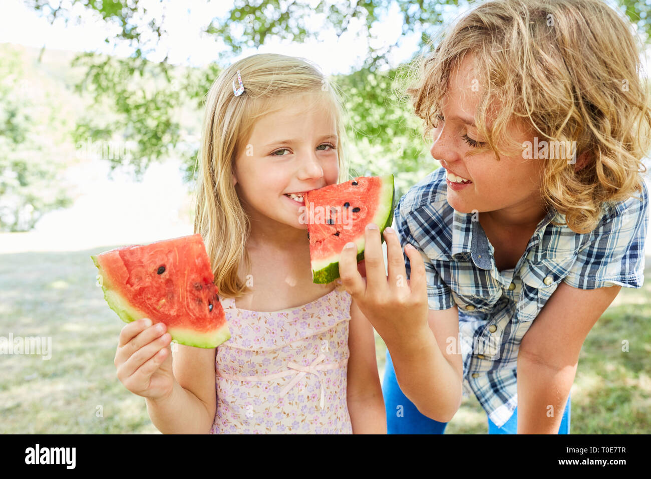 Kinder als Geschwister Essen, eine frische Melone zusammen als eine gesunde Ernährung Stockfoto