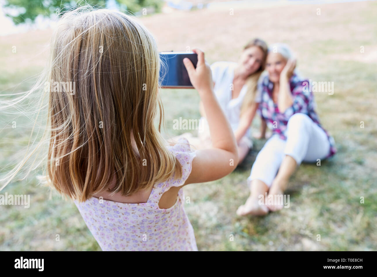 Kleines Mädchen nimmt ein Bild mit dem Smartphone von ihrer Mutter und Großmutter Stockfoto