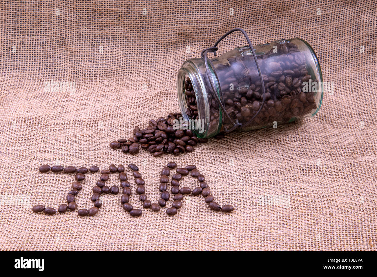 Kaffeebohnen, Java und ein antikes Glas mit Bohnen, verschüttet Stockfoto
