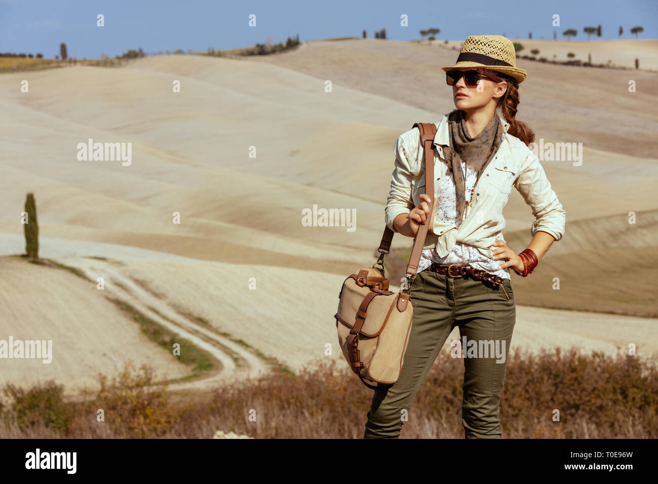 Junge solo touristische Frau in Wanderkleidung mit Tasche im Sommer in der Toskana Route in die Ferne schauen. Stockfoto