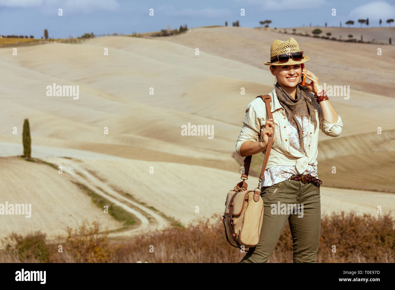 Portrait von lächelnden jungen Frau Wanderer in Wanderkleidung mit Tasche im Sommer Toskana Trail mit einem Handy. Stockfoto
