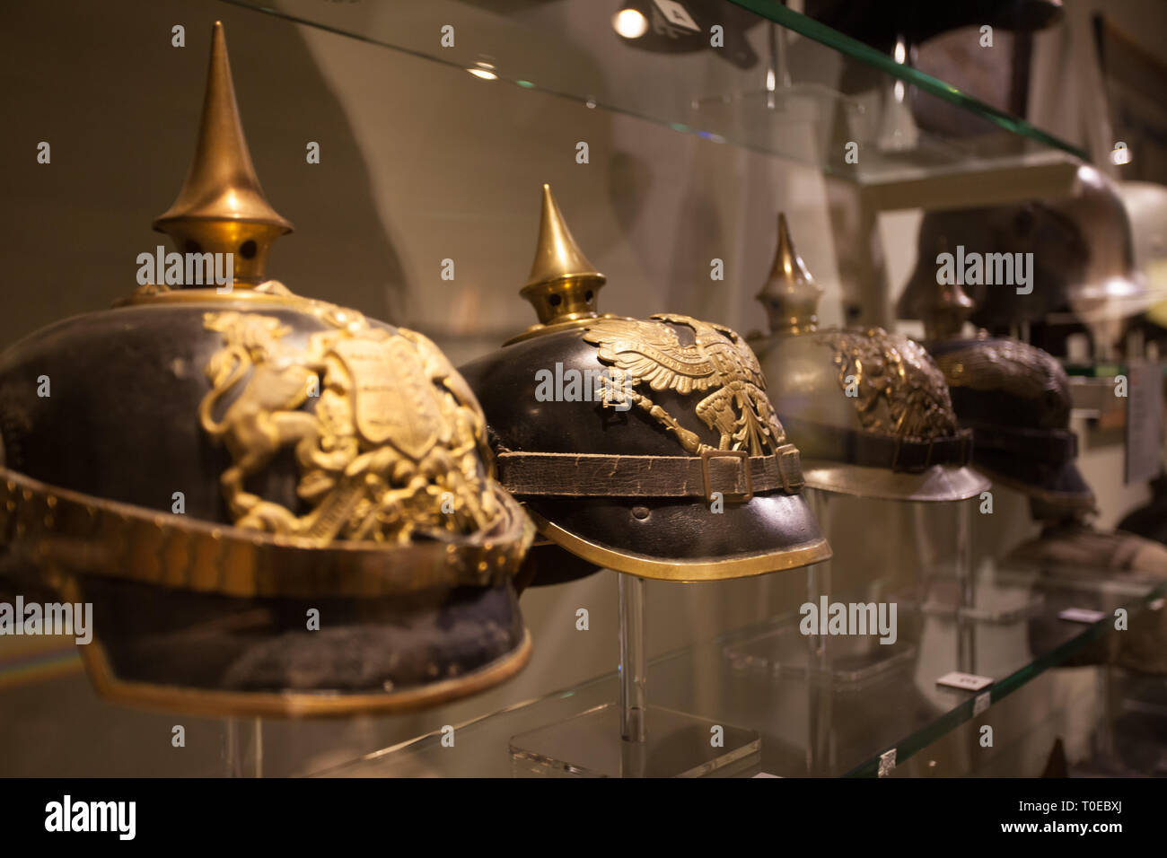 Deutsche Helme getragen während des Ersten Weltkrieges auf Display hinter Vitrinen in einem Museum. Sie sind schwarz mit Messing und eine Spitze auf der Oberseite. Stockfoto