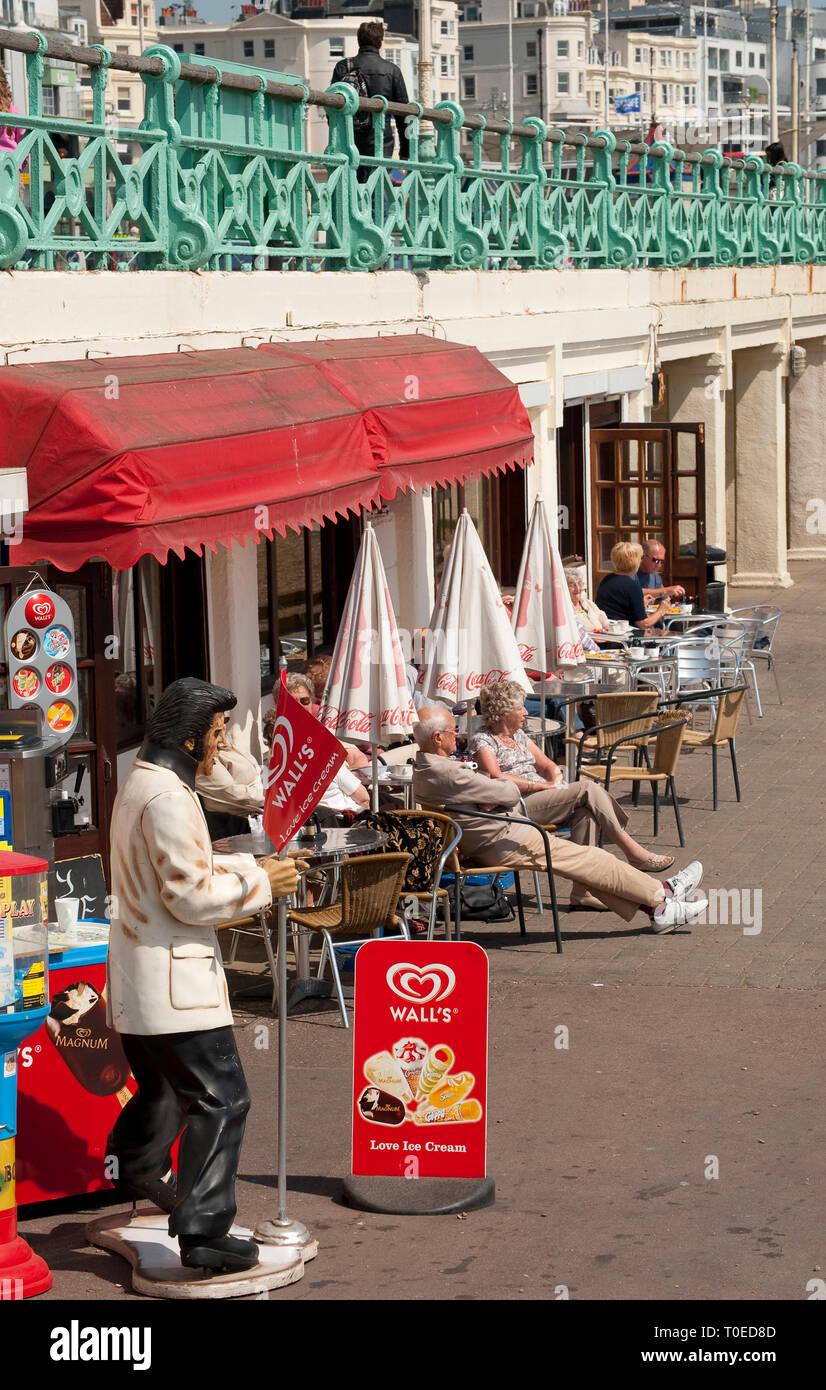 Urlauber genießen Sie Erfrischungen vor einem Cafe an der Strandpromenade von Brighton, Sussex, England sitzen. Stockfoto