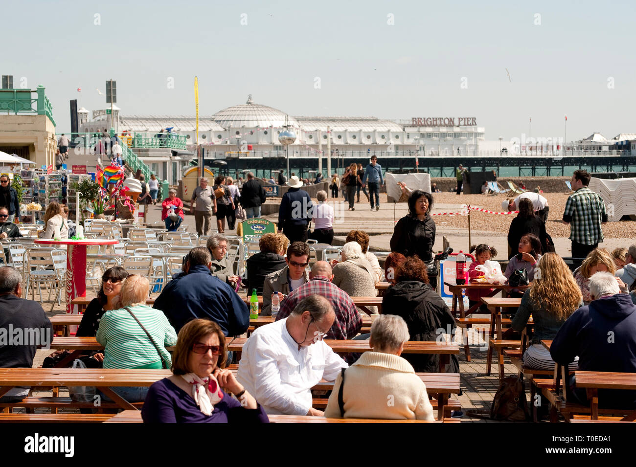 Urlauber genießen Sie Erfrischungen vor einem Cafe an der Strandpromenade von Brighton, Sussex, England sitzen. Stockfoto