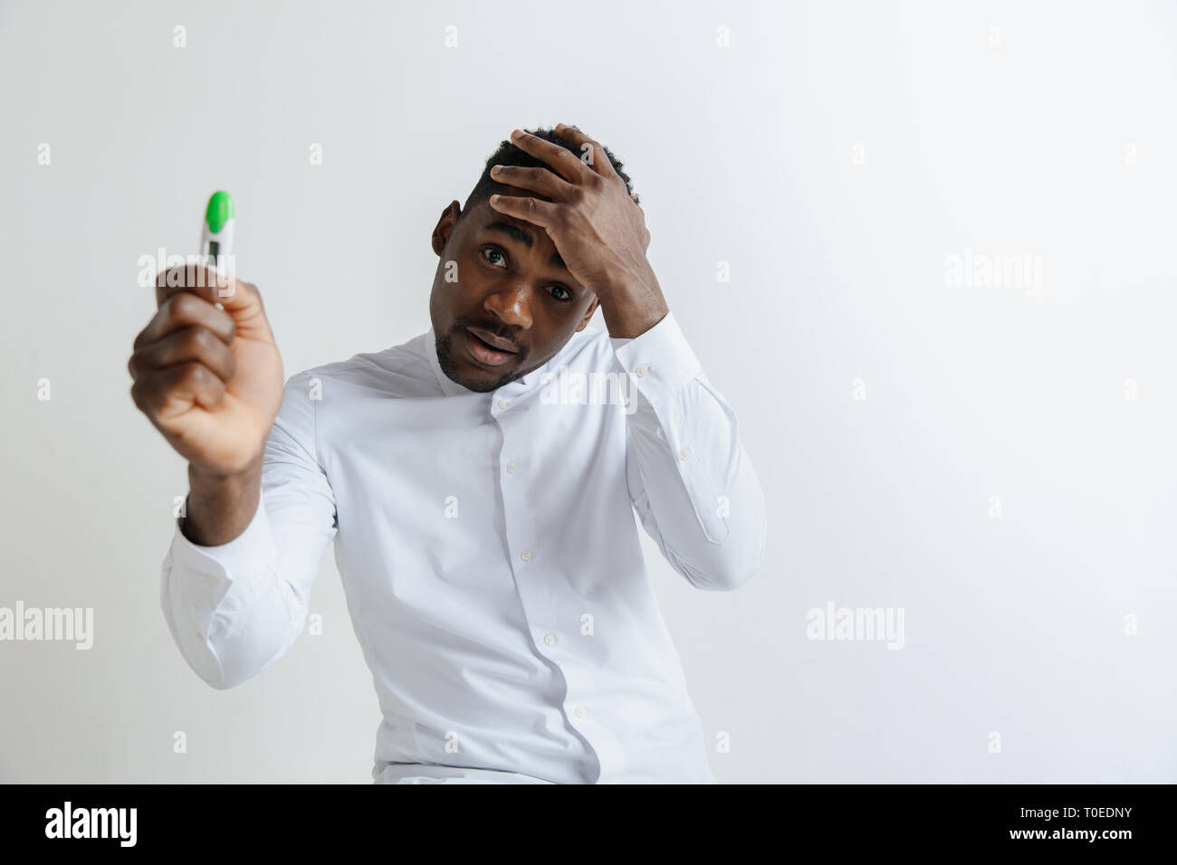 Junge unglücklich afrikanische amerikanische Mann an der Schwangerschaft Test suchen. Stattliche Mann traurig, frustriert und Probleme. Guy deprimiert, weil der aufgrund der Schwangerschaft Test Stockfoto