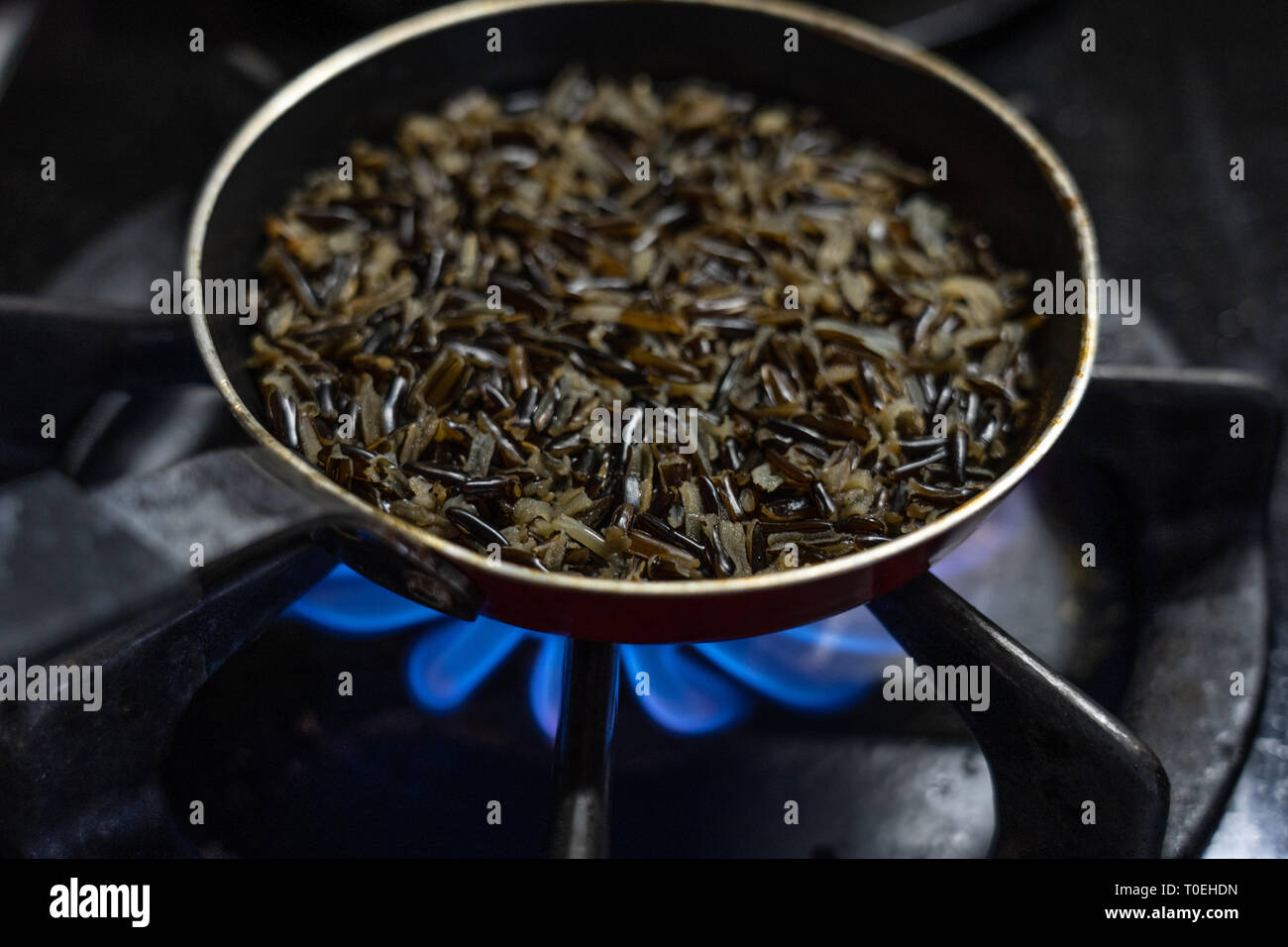 Wilder Reis kochen auf dem Herd in einem Topf über einem Feuer in einer Küche Stockfoto