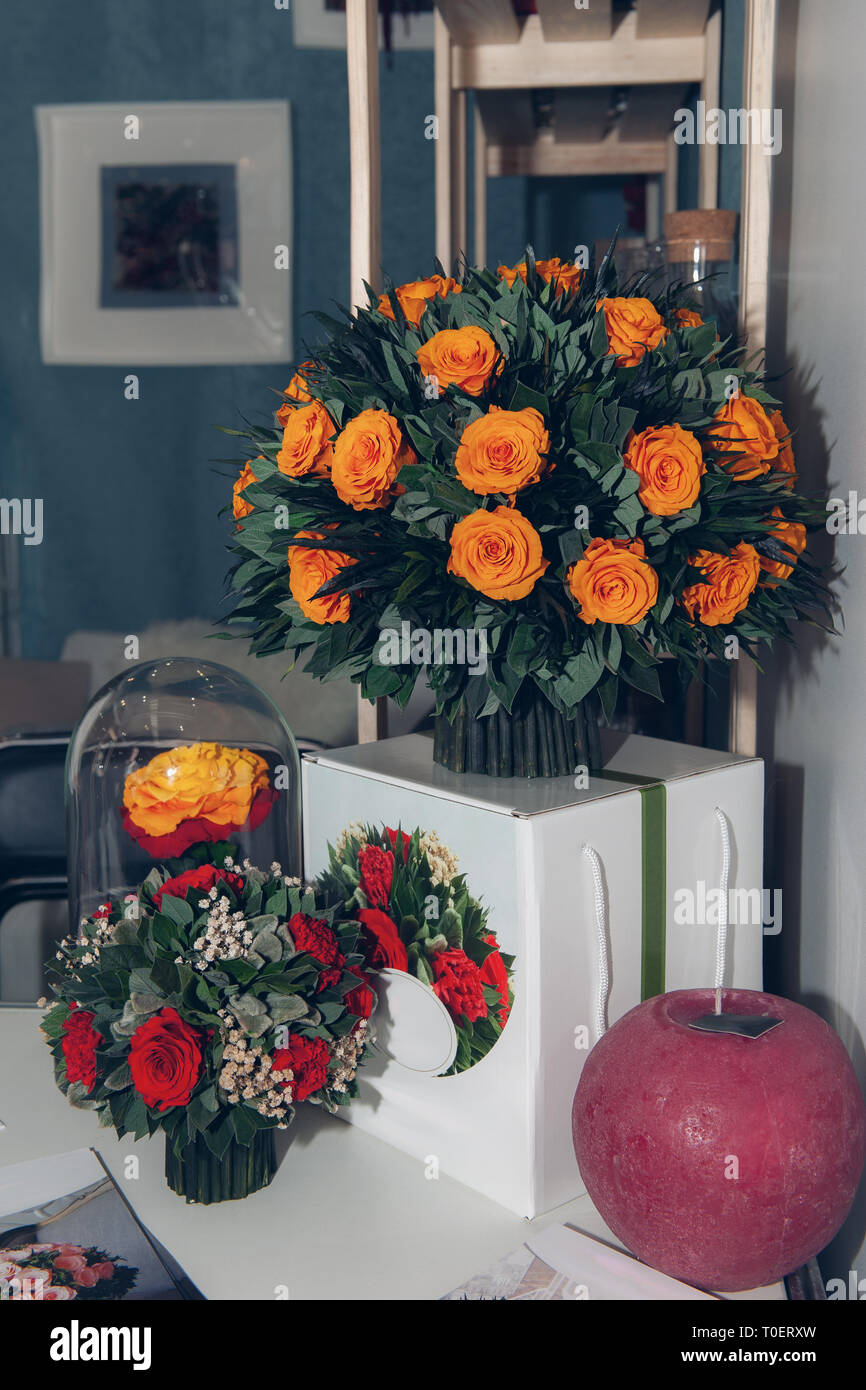 Ein großer Blumenstrauß aus schönen orange Rosen im Innenraum auf einem weißen Nachttisch ausgestattet. Stockfoto