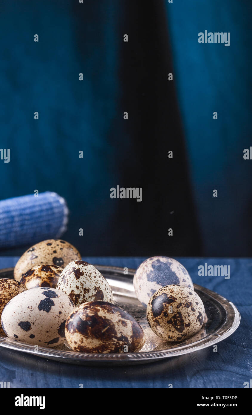 Mehrere Eier von der Wachtel auf Silber, oval Tablett auf einer blauen Tabelle. Stockfoto