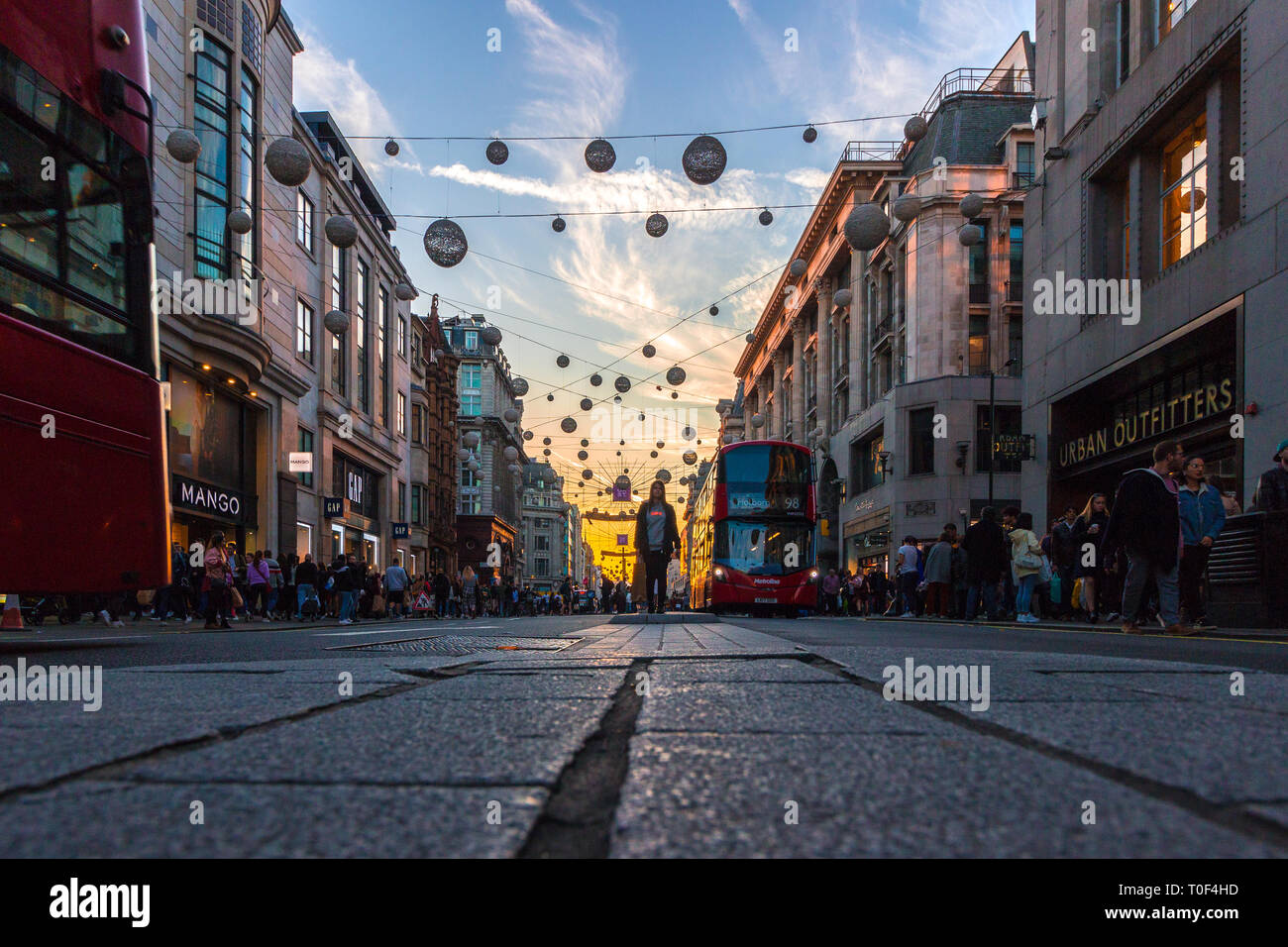 Regents Street, London. Eine niedrige schräg von der berühmten Straße, mit einem roten London Bus hinunter Ansatz und dekorative Leuchten über der Straße aufgehängt Stockfoto