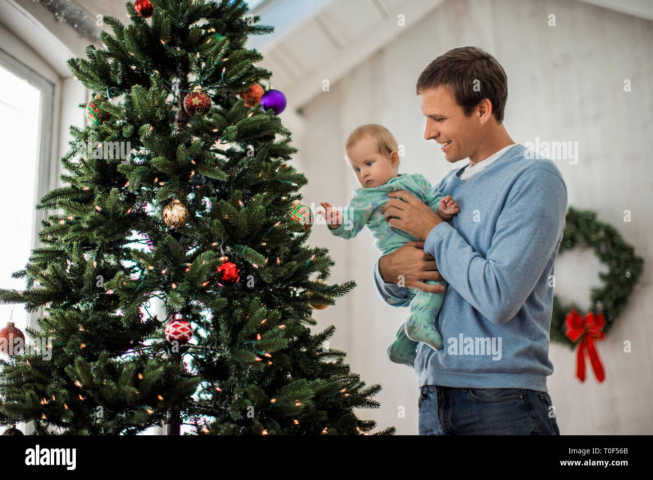 Gerne Vater schmücken einen Weihnachtsbaum mit seiner kleinen Tochter. Stockfoto