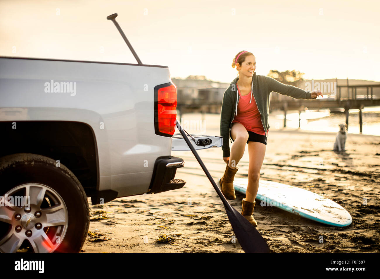 Lächelnde junge Frau auf ihrem Hausstiefel nach paddleboarding. Stockfoto