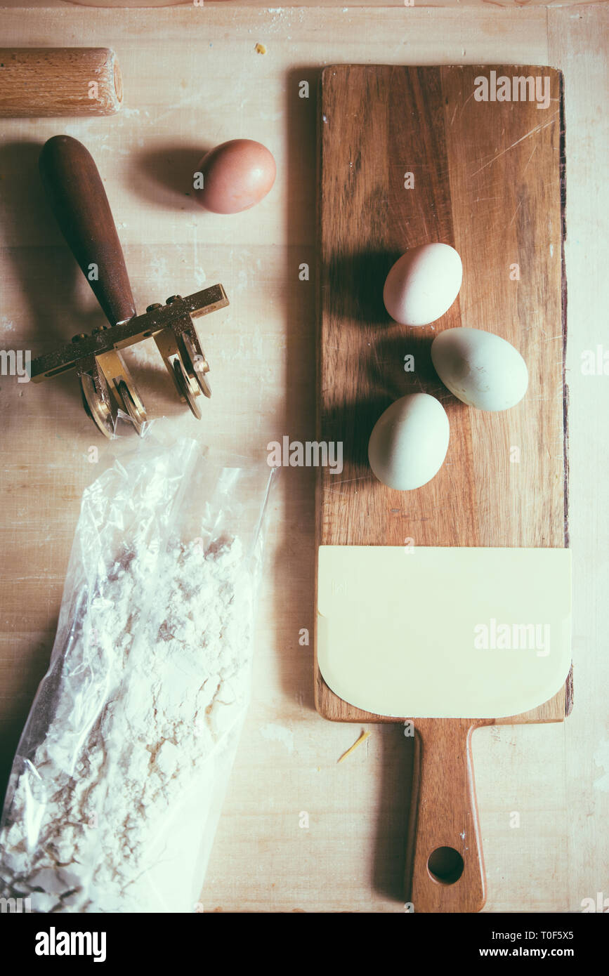 Die pasta zu Hause, natürlichen, grünen Ei, Olivenöl, Egger, weiße und braune Eier, Mehl und Pasta cutter über eine Holz- Hintergrund Stockfoto