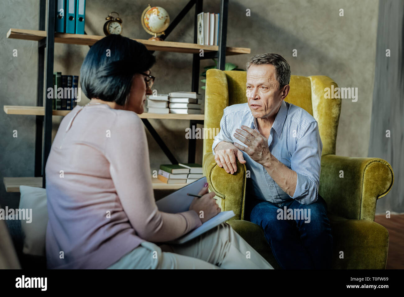 Expressive unangenehmen Mann lehnte sich auf dem Sofa und aktiv Gestik Stockfoto