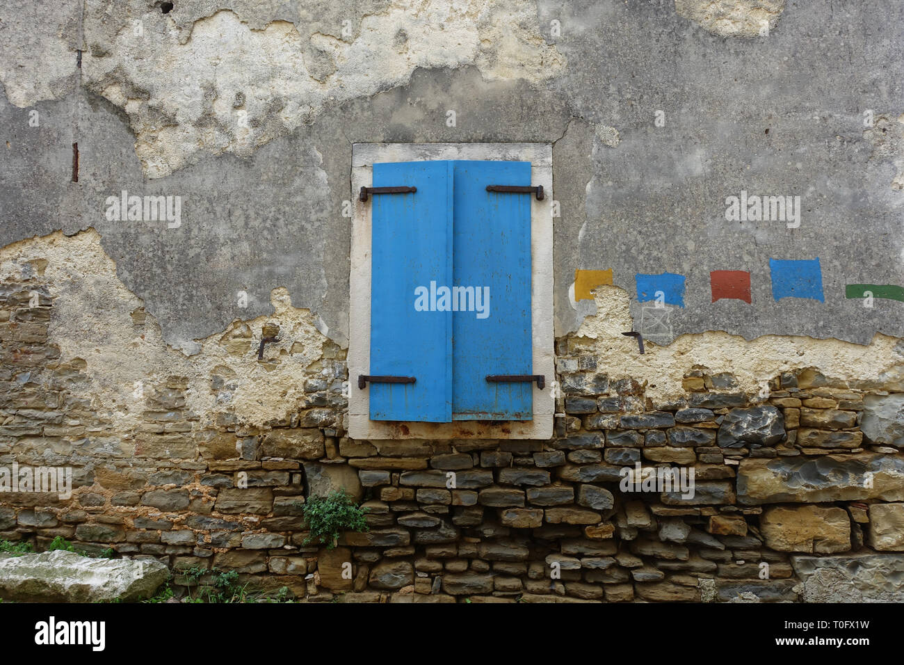 Farbenfrohe blaue Fenster, die gegen eine alte Mauer aus Stein, die in einer kleinen Stadt in Kroatien Stockfoto