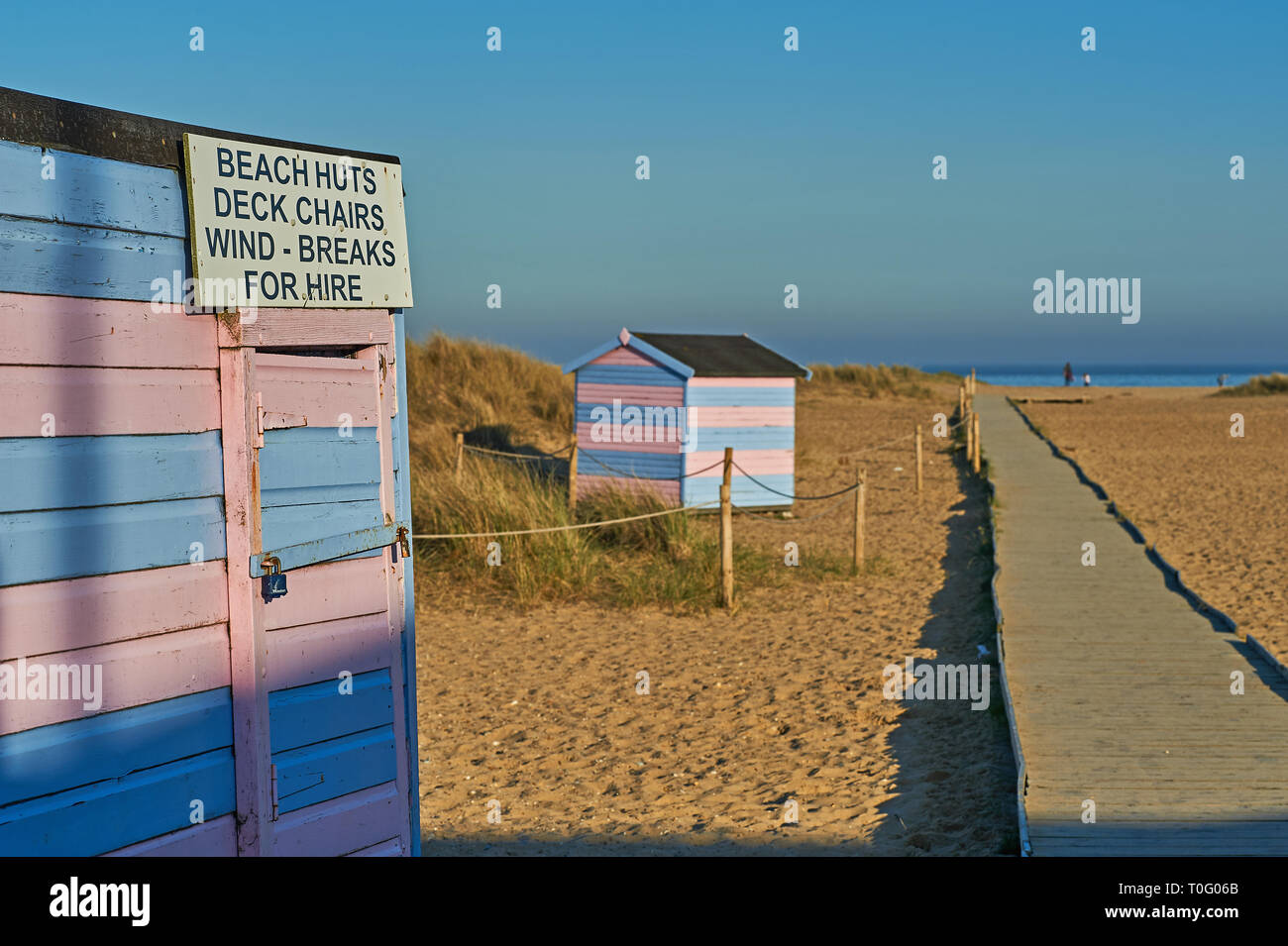 Traditionelle Seaside Beach Huts in blau und rosa Streifen auf den Schindel Küstenstreifen in Great Yarmouth, Norfolk Stockfoto