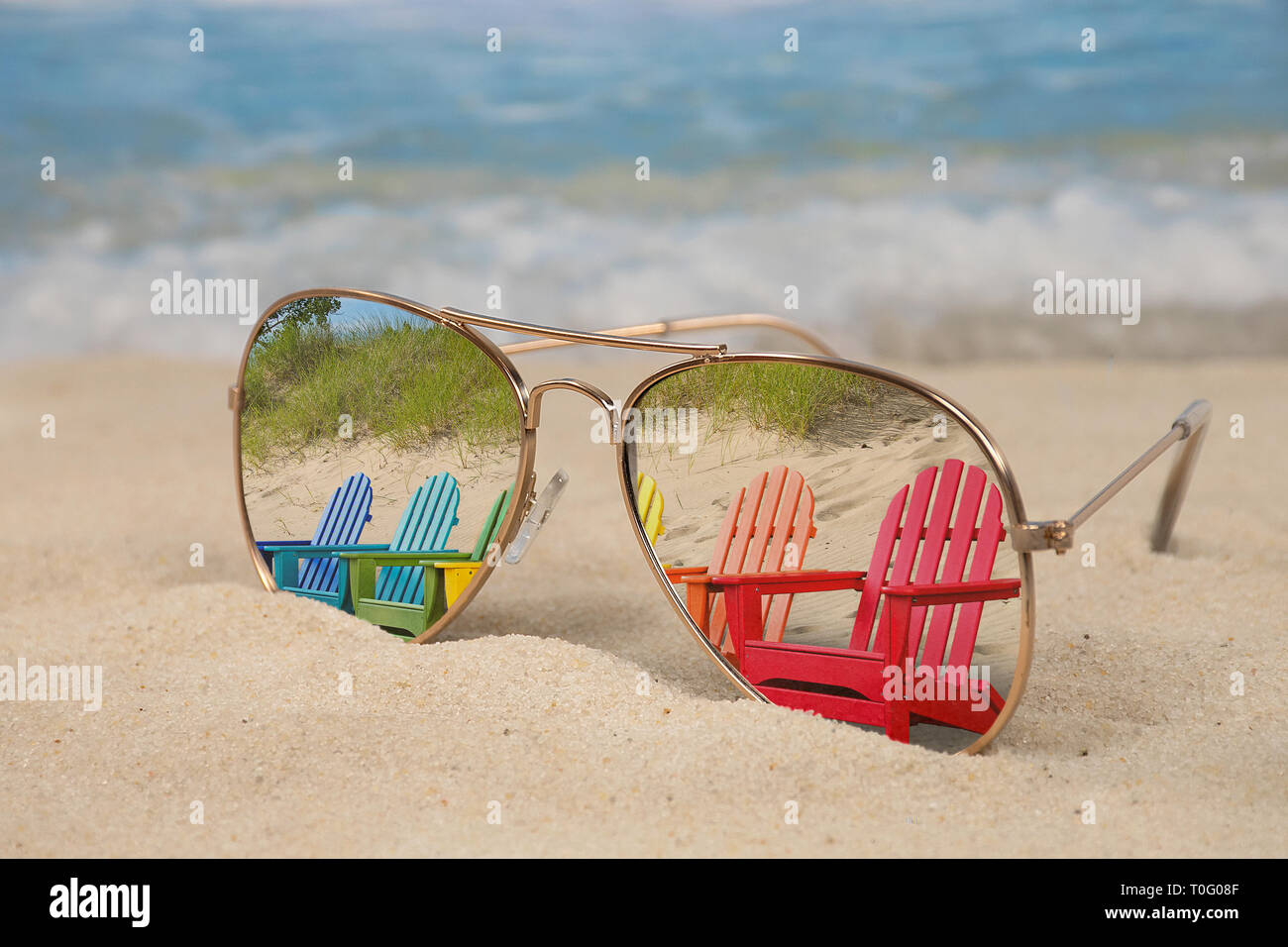 Bunte Reihe der Adirondack Stühle in Aviator Sonnenbrille im Strand Sand reflektiert Stockfoto