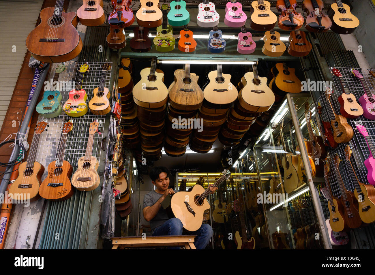 Ein Mann, der an seine Gitarre shop, Ho Chi Minh City, Vietnam Stockfoto