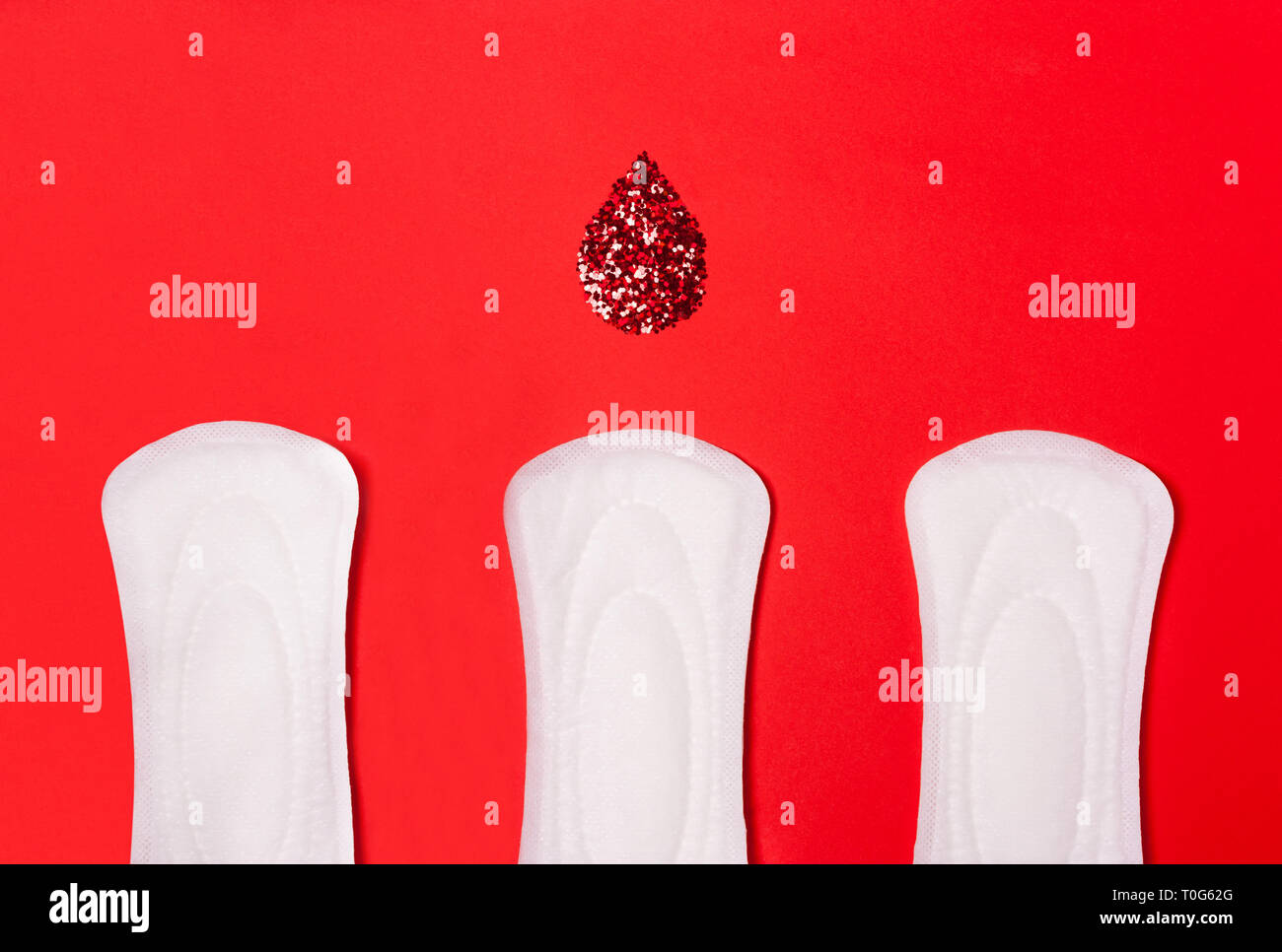 Drei Damenbinden auf eine Koralle rot hinterlegt. Das Konzept der kritischen Tagen, Menstruation, Frauen regelmäßigen Zyklus. Stockfoto