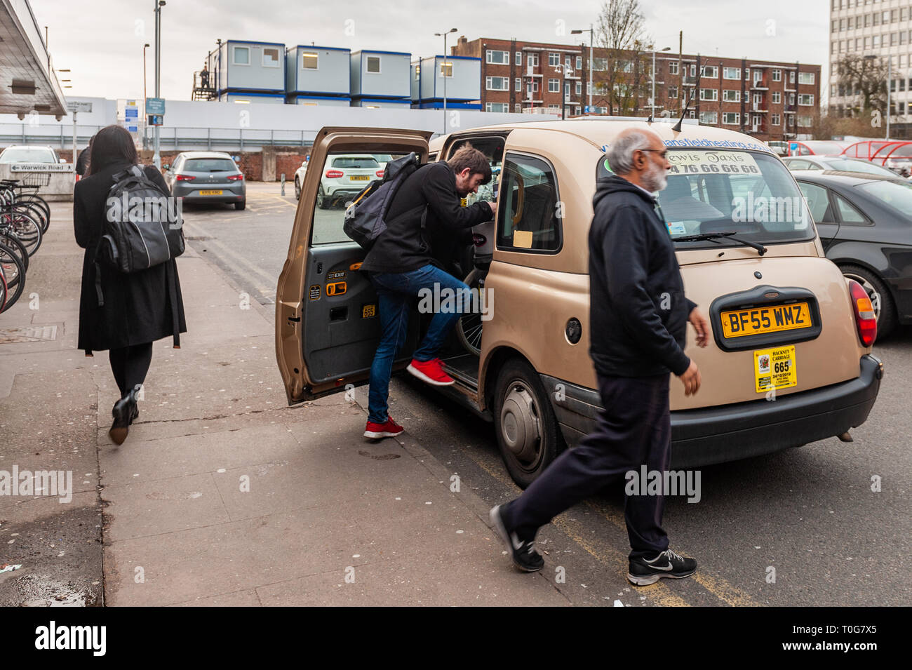 Mann bekommt, in ein Taxi vor dem Bahnhof Coventry, Coventry, West Midlands, UK. Stockfoto