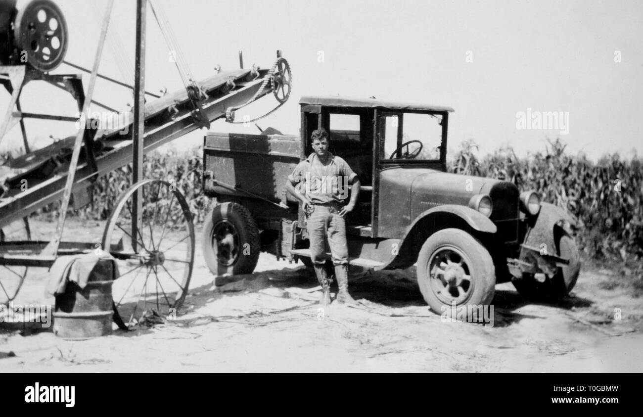 Eine Nebraska mais Landwirt steht durch seine Erntemaschinen, Ca. 1930. Stockfoto