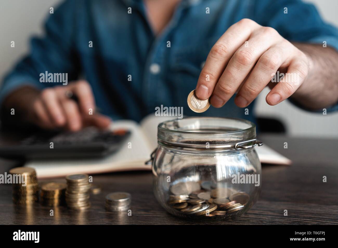 Business Accounting mit Geld sparen mit Hand Münzen im Krug Glas Konzept finanzielle Stockfoto