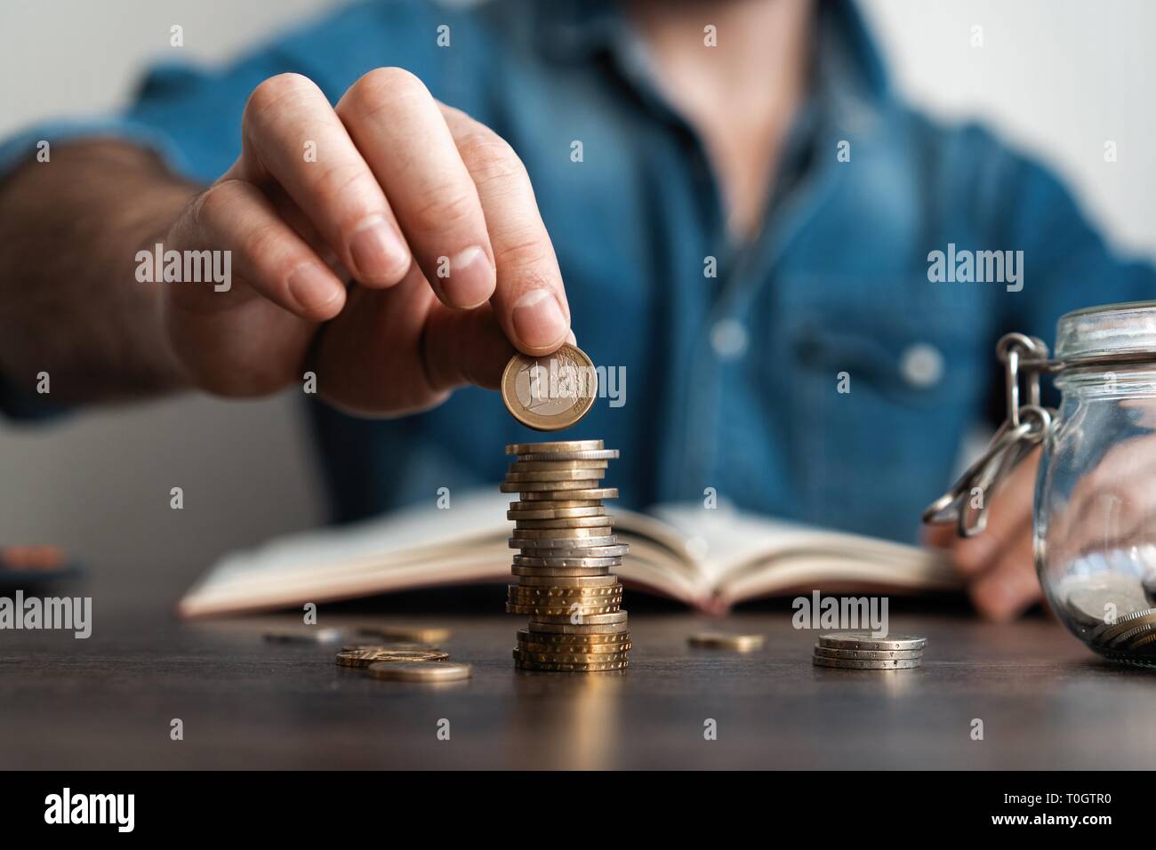 Business Mann, eine Münze auf Münzen Stapel speichern Bank und für sein Geld Konto alle in die Finanzbuchhaltung Konzept Stockfoto