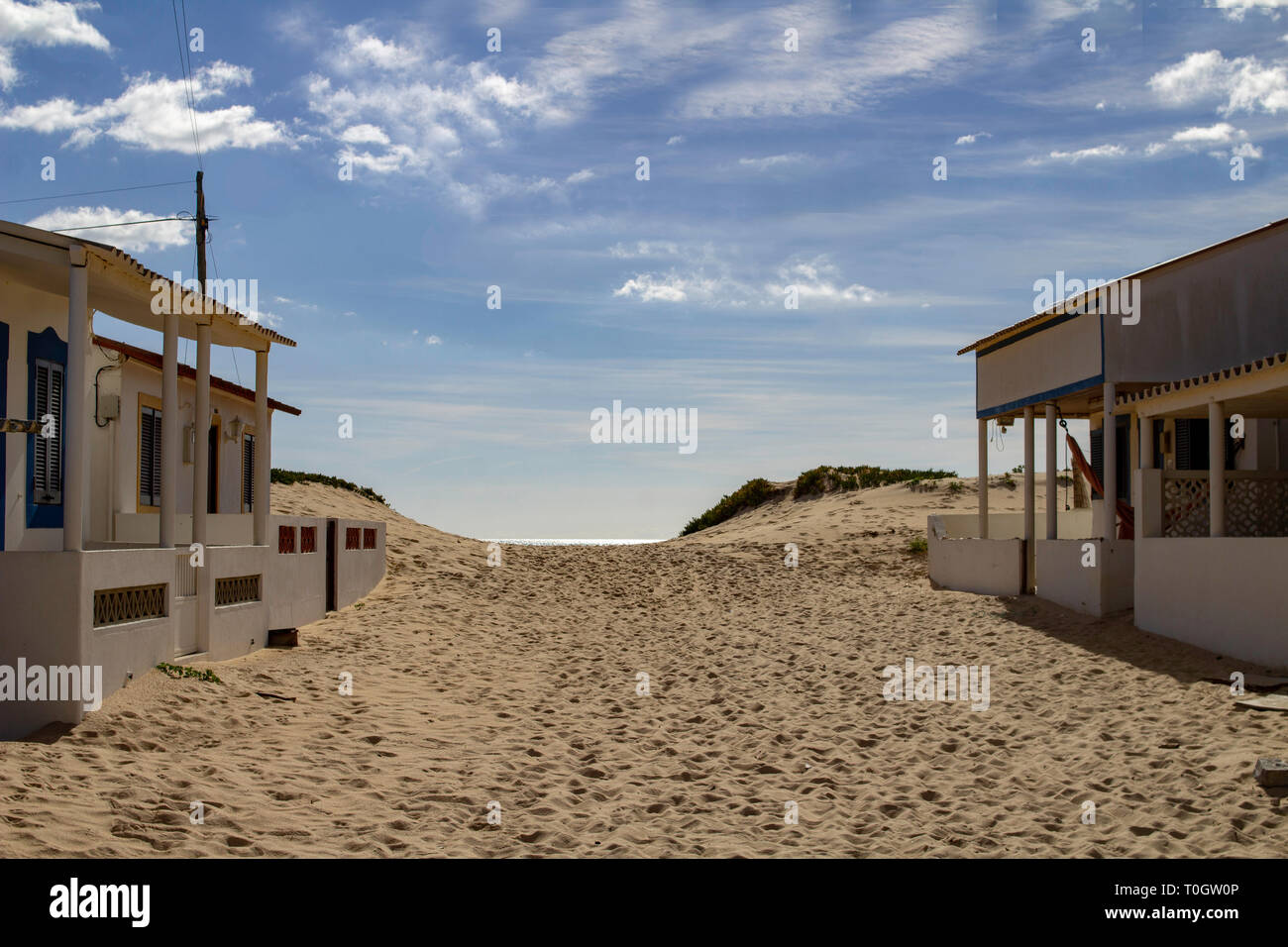 Faro, Portugal.EINE Strandszene in Faro Beach, Portugal umrahmt von Strandunterkünften, dem Meer im Hintergrund und einem blauen Himmel. Stockfoto