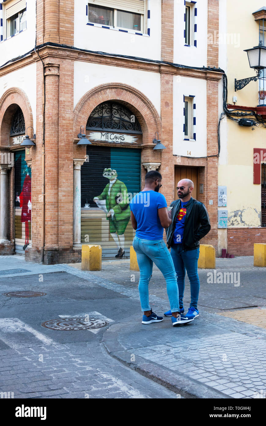 Zwei Männer, die in der Nähe einer Bar mit Fensterläden in Sevilla Stockfoto