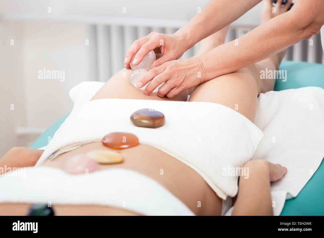 Frauen, die Oberschenkel Massage mit Stein Stockfoto