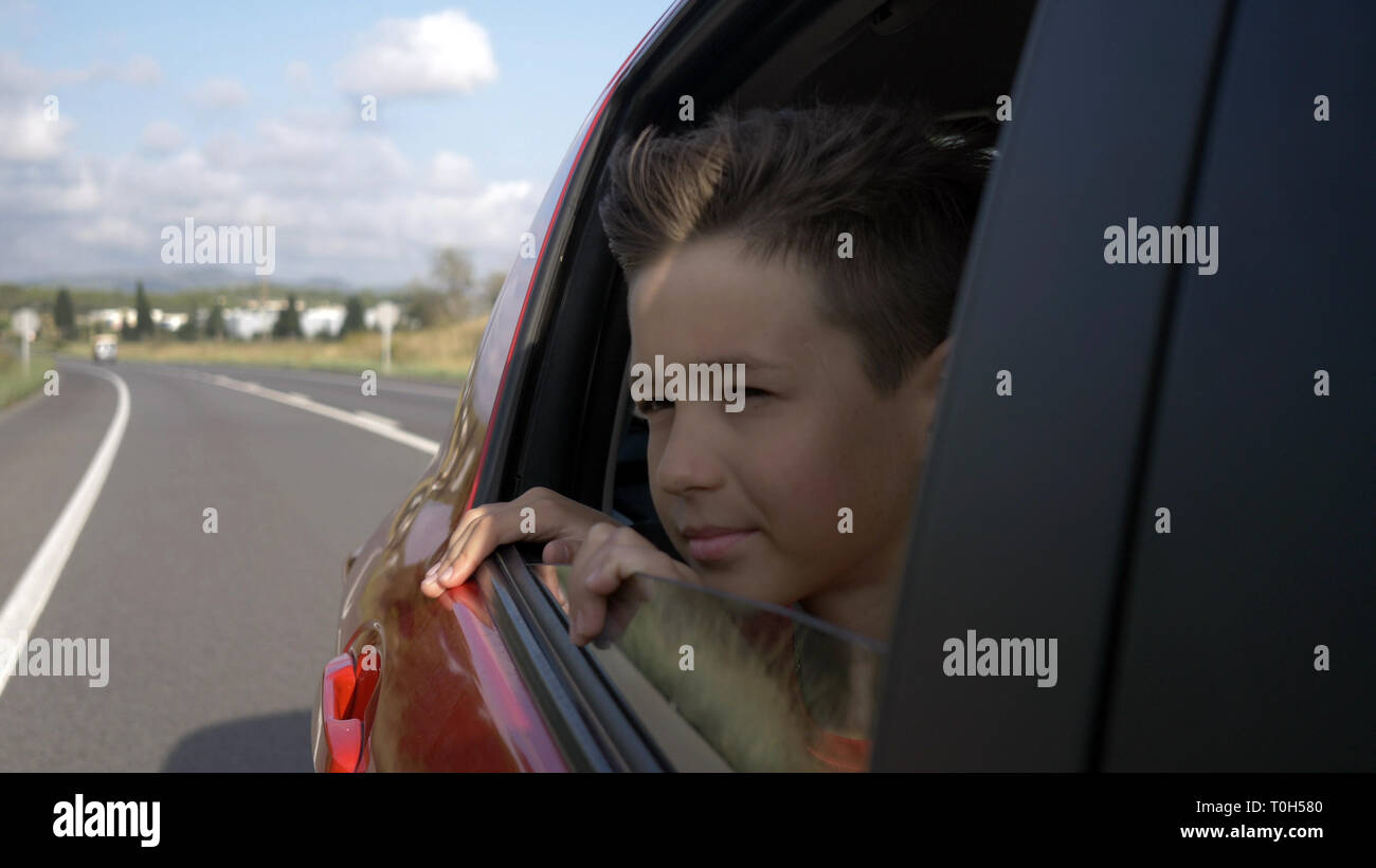 Happy Boy Reiten in einem Auto mit offenem Fenster und außerhalb suchen, der Wind Haar entwickelt, haben Spaß Stockfoto