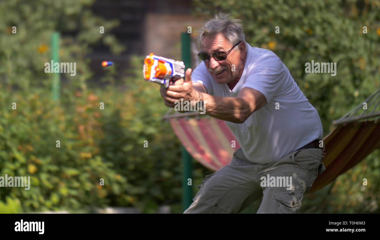 Älterer Mann mit spielzeugpistole Kampf auf die Natur Stockfoto