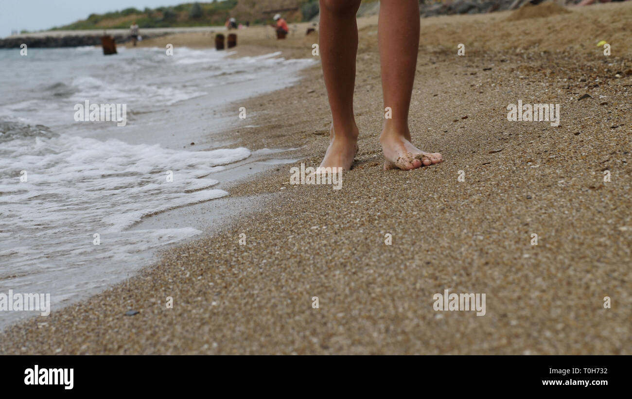 Junge ist zu Fuß entlang der goldenen Sand am Strand am Abend, Füße close-up Stockfoto