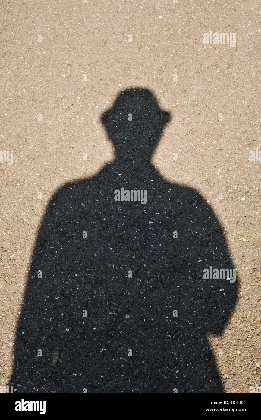 Schatten eines Mannes mit Trilby Hut auf dem Asphalt Stockfoto