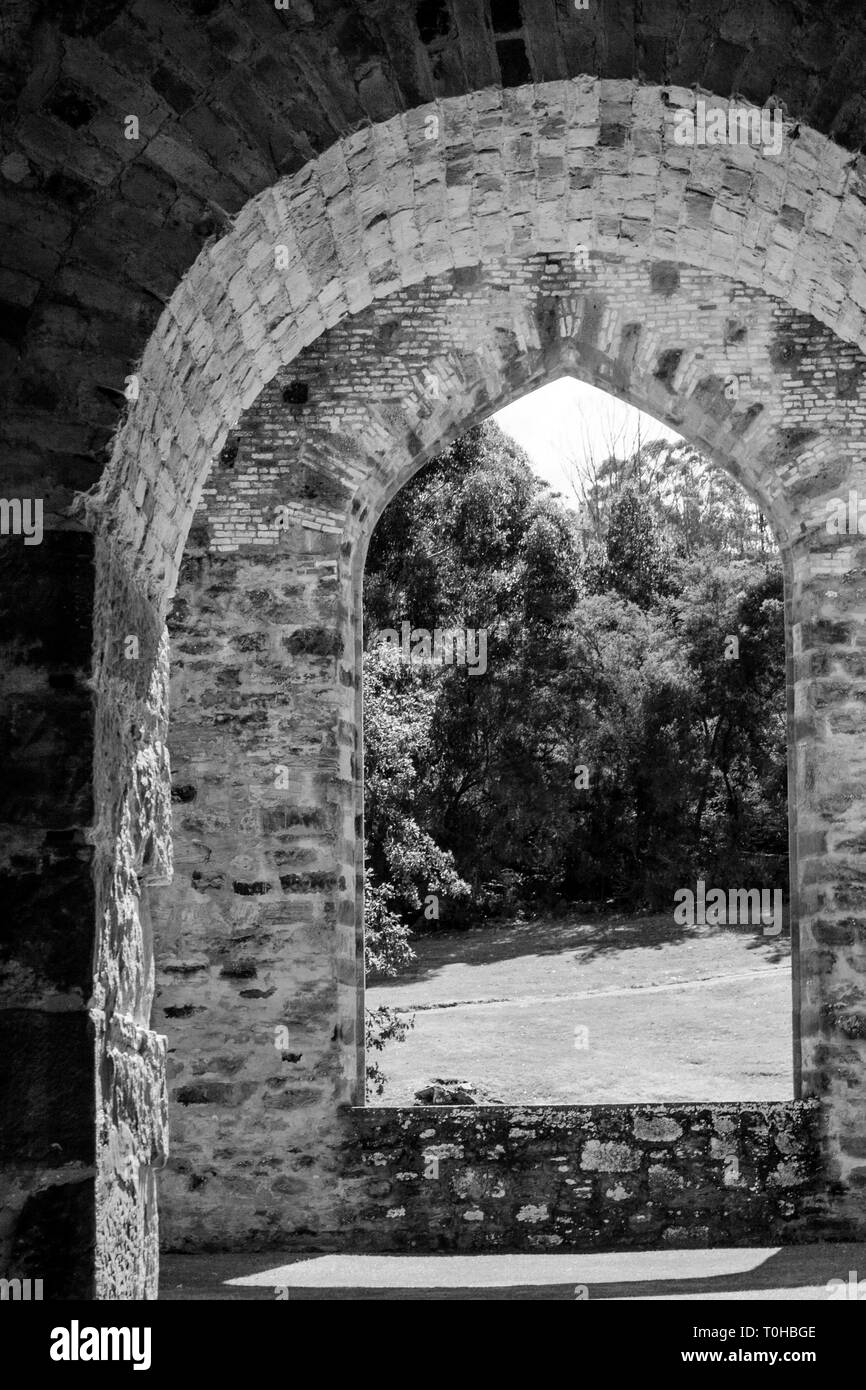Ein Blick auf den Garten durch eine runde Torbogen und einem spitzen Bogenfenster eingerahmt. Schwarz-weiß-Bild. Stockfoto