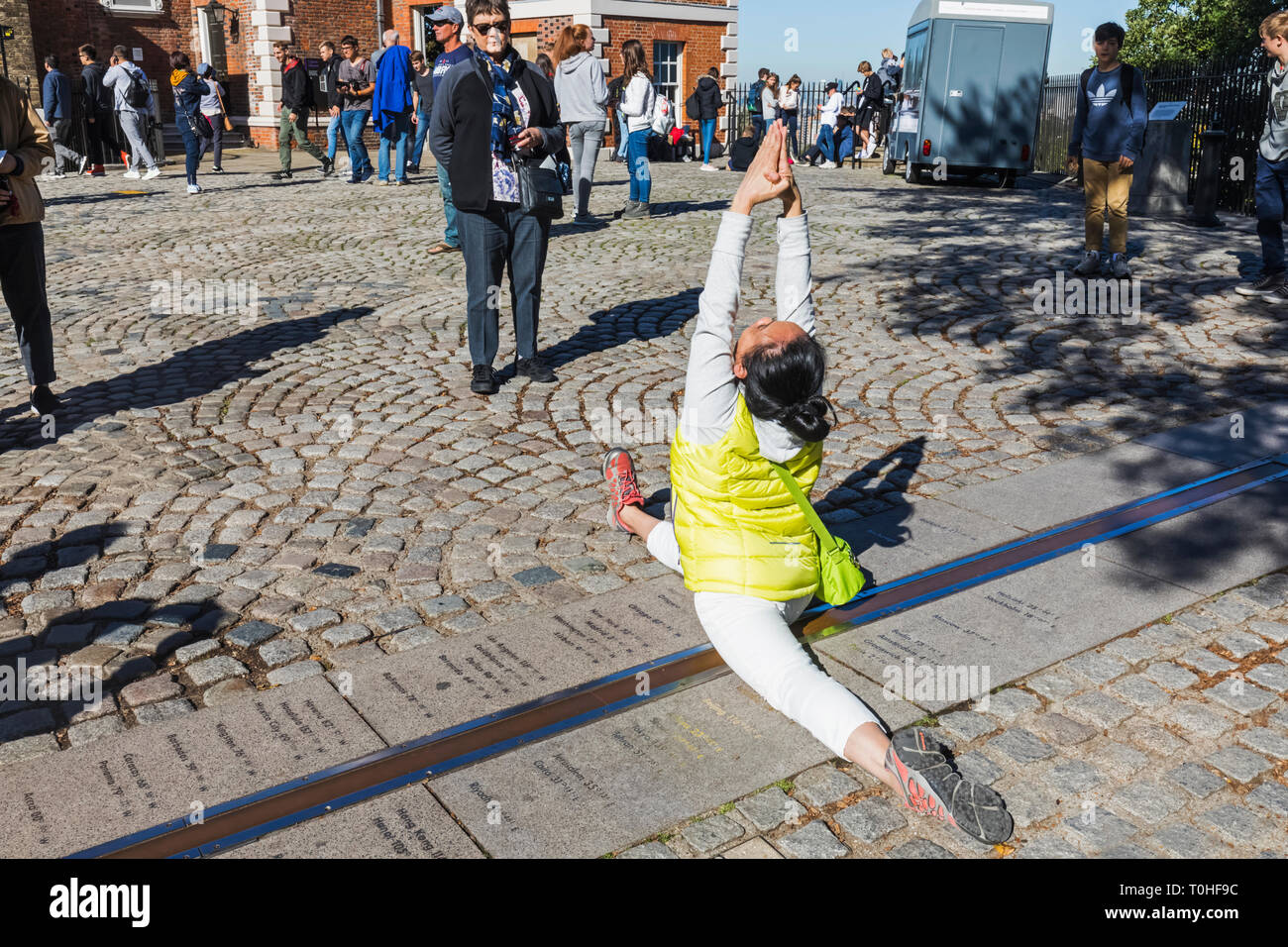 England, London, Greenwich, Royal Observatory, asiatische Touristen, die an beiden Seiten des Greenwich Meridian Line Stockfoto