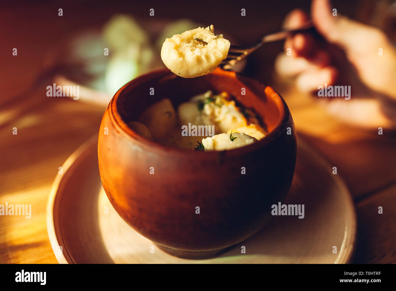 Leckere Knödel mit Huhn und Dill in Lehmtöpfen und Getränke im Café serviert. Ukrainische traditionelles Essen. Nationale Küche Stockfoto