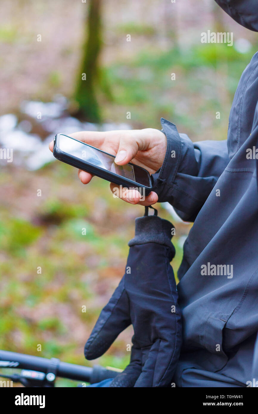 Traveler Hand steht mit einem Fahrrad- und Holding smart phone Gerät im Wald Stockfoto