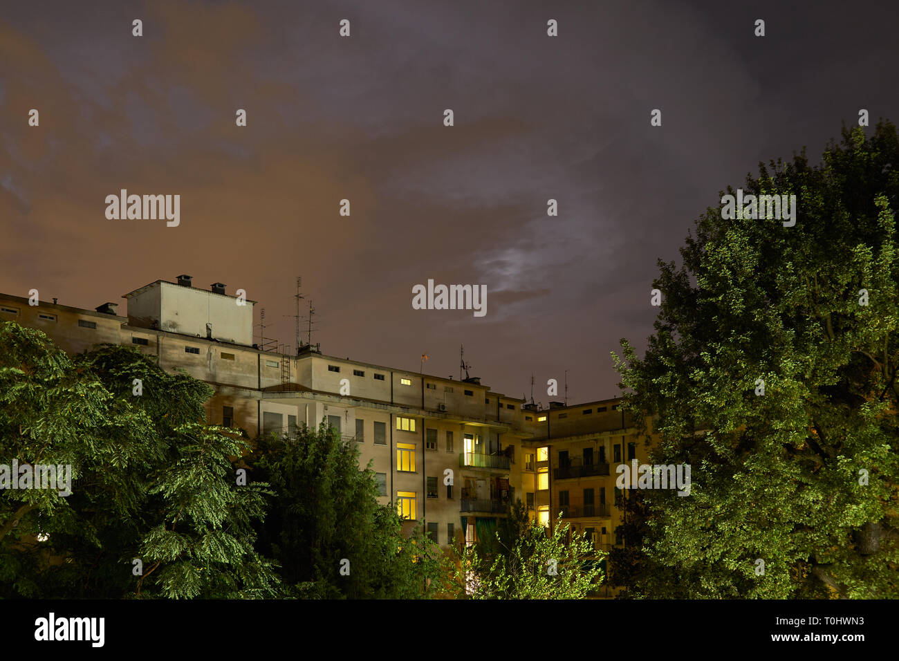 Gebäude und grüne Bäume bei Nacht, beleuchtete Himmel im Sommer Stockfoto