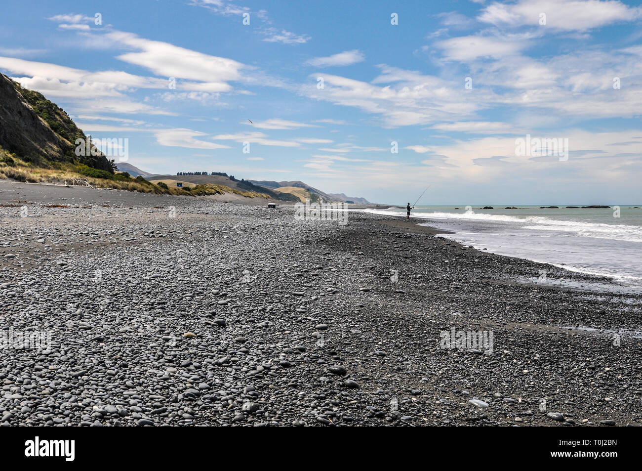 Einsame angler angeln. Schwarzer Sandstrand an der Ostküste der Südinsel Neuseelands in der Region Canterbury. Pazifik Küste Stockfoto