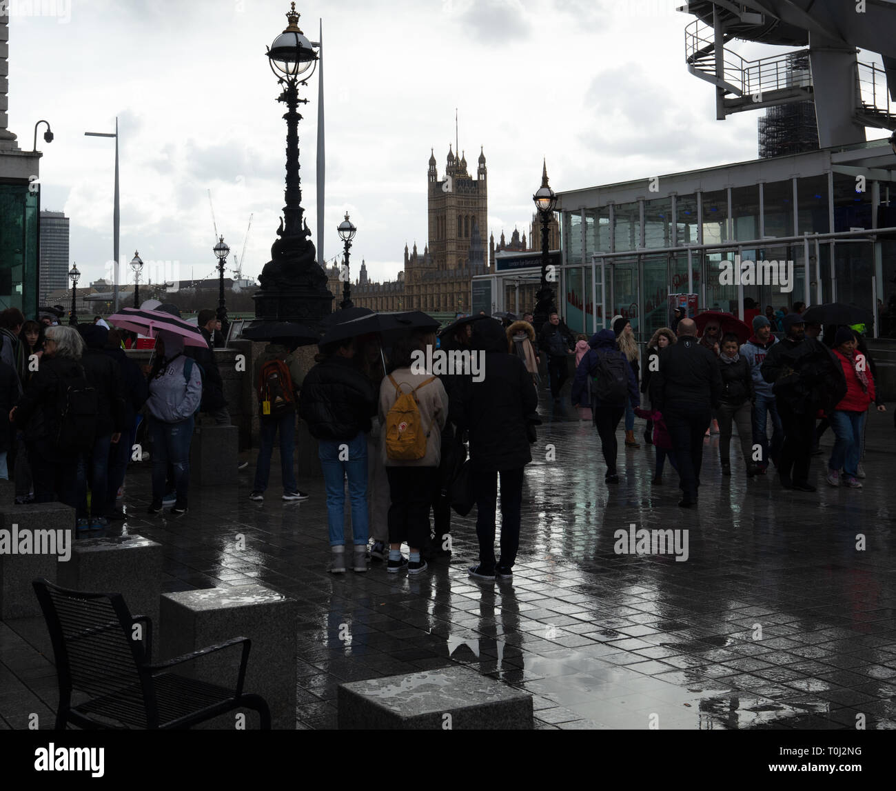 Touristen können Sonnenschirme und andere Regen deckt auf diesem nassen und feuchten Tag trocken auf der South Bank am Fuße des London Eye in London zu bleiben. Stockfoto