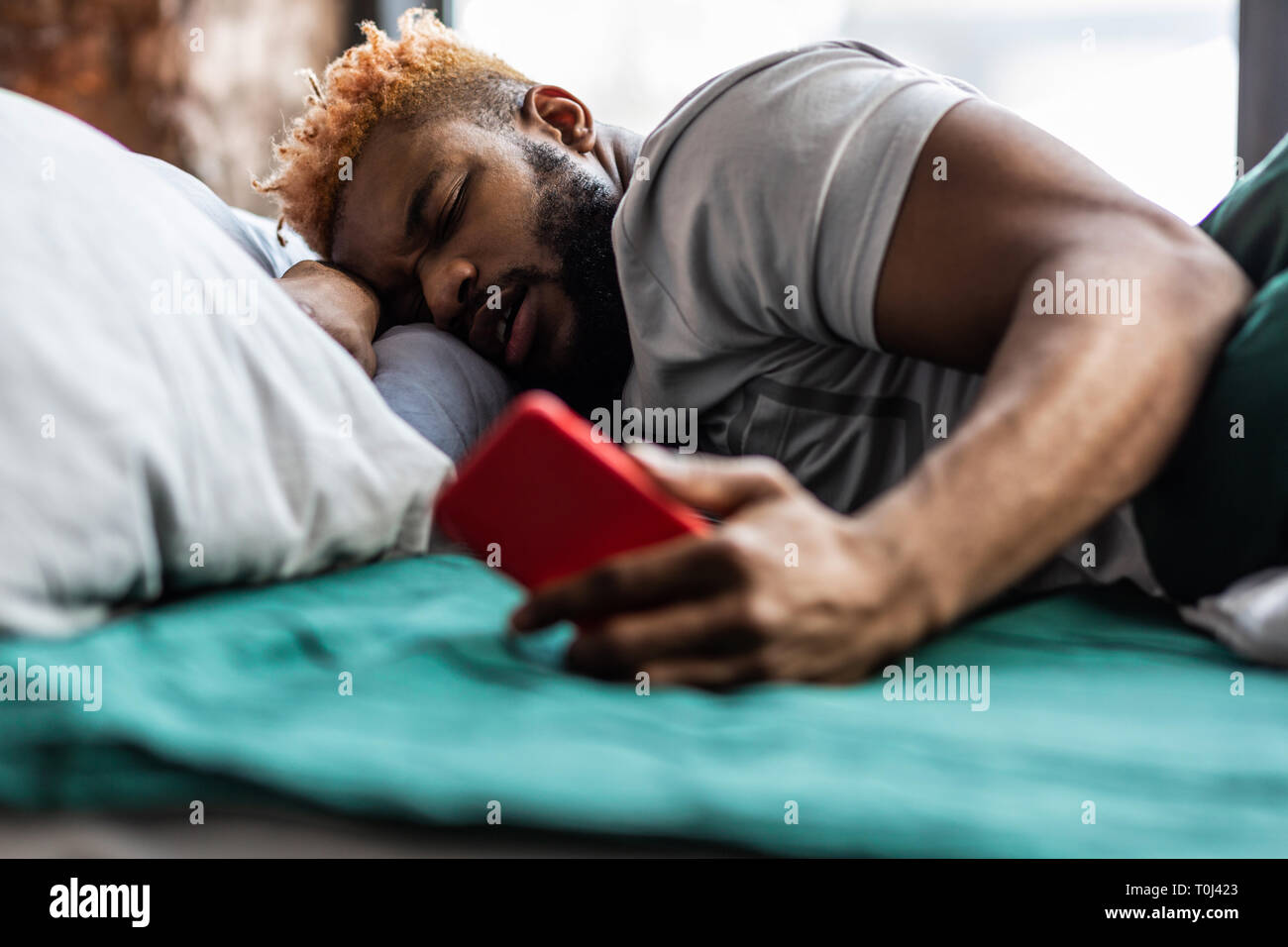 Angenehmen, netten Mann an seinem Bildschirm des Smartphones auf der Suche Stockfoto