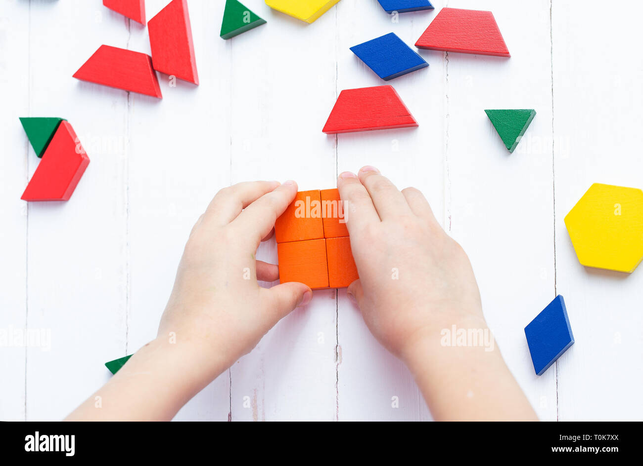 Ein Kind spielt mit farbigen Bausteinen konstruiert ein Modell auf einem hellen Hintergrund Stockfoto
