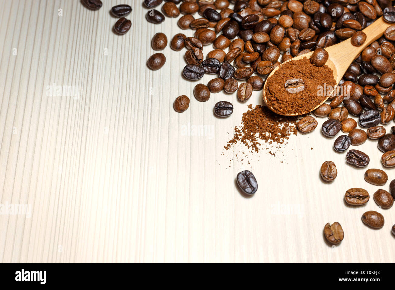 Geröstete Kaffeebohnen und gemahlener Kaffee in hölzernen Löffel auf Leuchtkasten. Nahaufnahme mit Platz für Text. Stockfoto