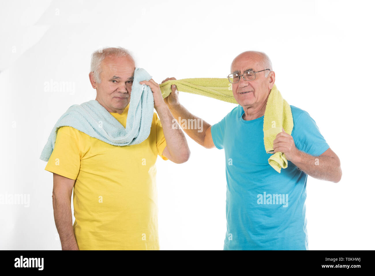 Zwei glücklich lächelnde ältere Männer nach dem Sport Training mit gelben und blauen T-shirts und Handtücher Stockfoto