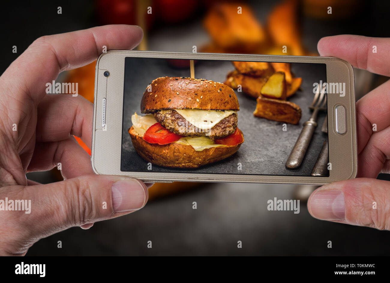 Mann, Foto von traditionellen Cheeseburger mit Rindfleisch und gebratenen Kartoffeln Stockfoto