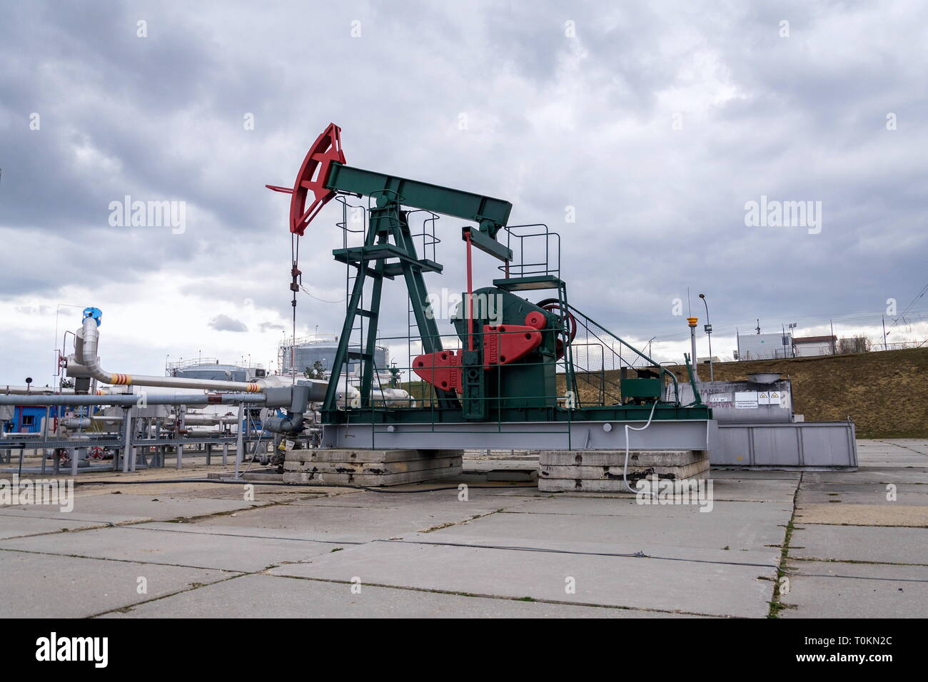 Grüne und rote Pferd pumpjack, Öl, Öl derrick Öl gut Pumpen mit dramatischen bewölkter Himmel Hintergrund Stockfoto